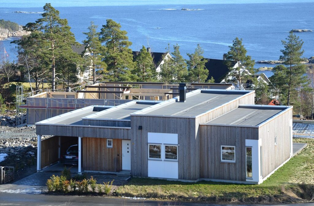Wood-clad modular home nearing completion among pine trees by the sea in Risør, Norway