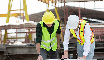Two managers reviewing drawings on a job site