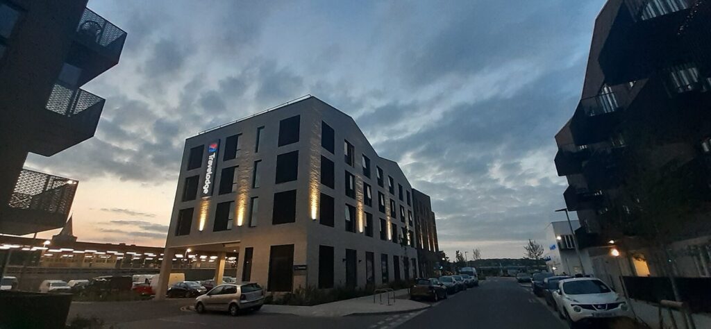 Modern modular hotel building at dusk with lit windows on a riverside street in Rochester, Kent
