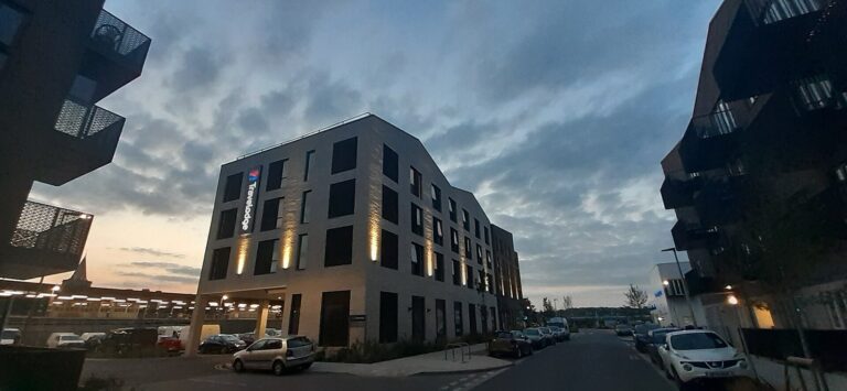 Modern modular hotel building at dusk with lit windows on a riverside street in Rochester, Kent