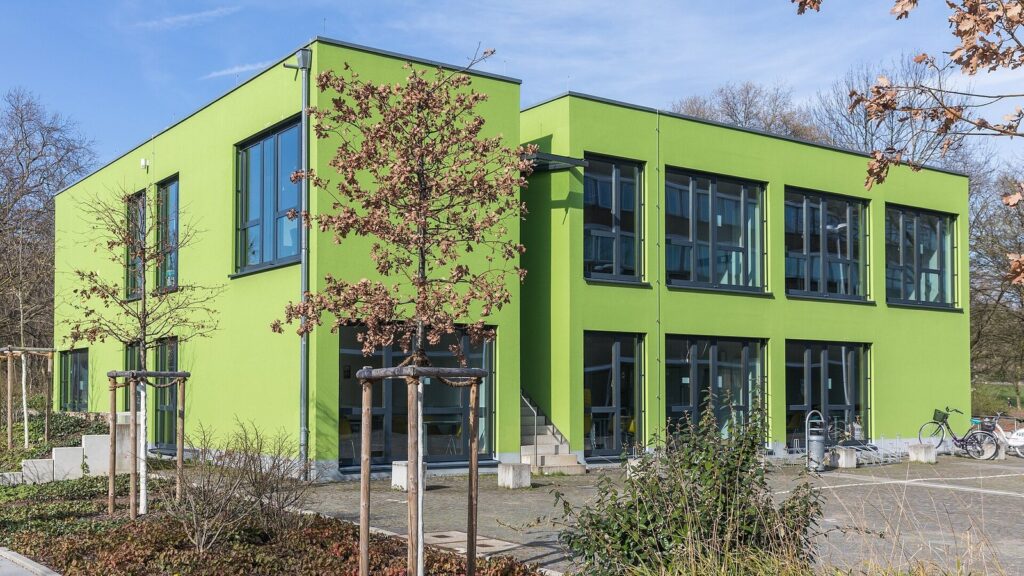 Two-story bright green modular university building with large windows in Cologne, Germany