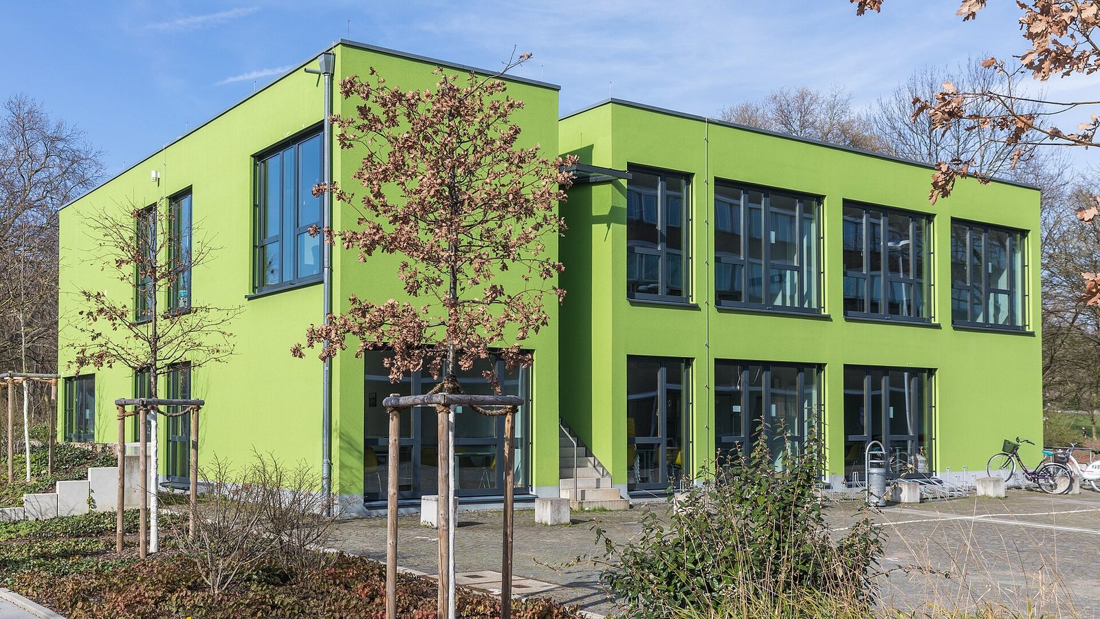 Two-story bright green modular university building with large windows in Cologne, Germany