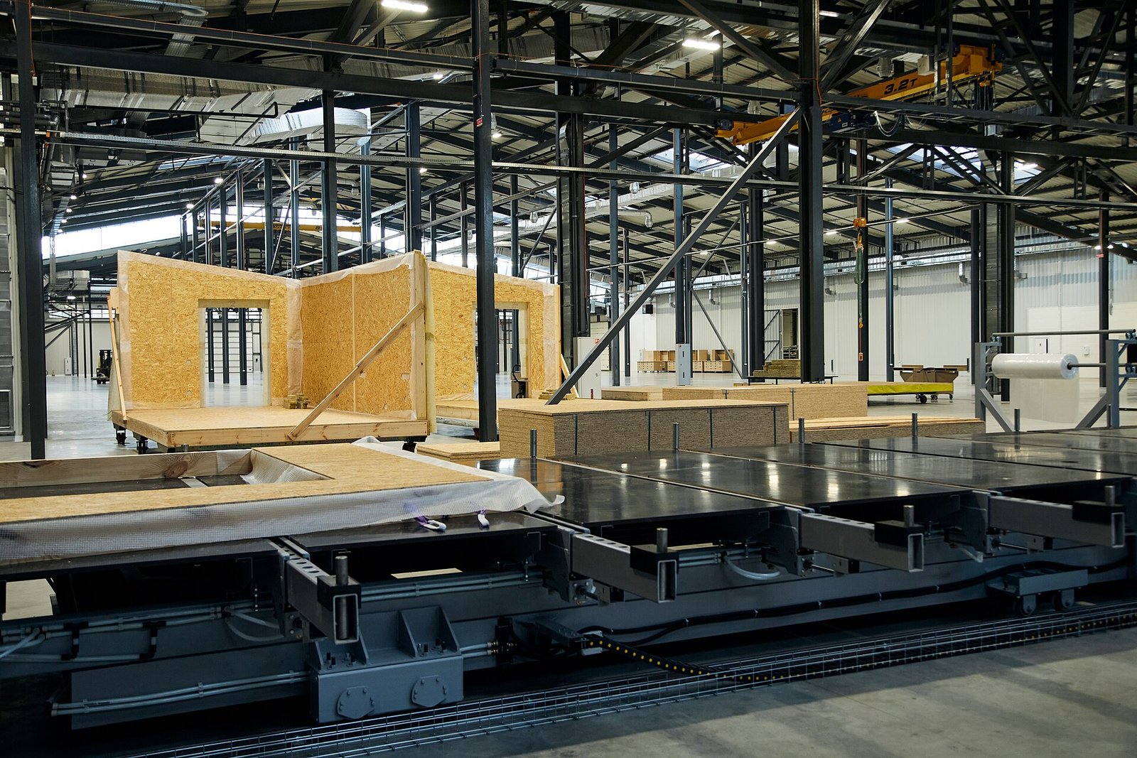 Workers assembling timber house components on the production floor of a prefab home factory
