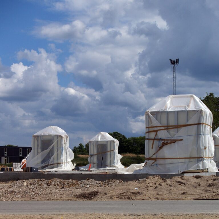 Wrapped prefabricated bathroom pods standing on a building site waiting for the surrounding walls