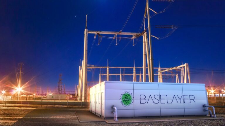 Modular data center enclosure lit at night beside a high voltage utility substation