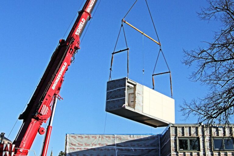 A crane lowers a factory-built module into place on a hospital expansion site.